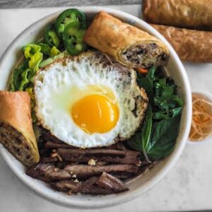 A vibrant Vietnamese pho bowl with egg and spring rolls, perfect for a healthy meal.