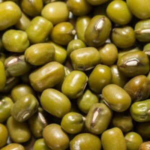 Macro photograph of fresh green mung beans, highlighting texture and color.